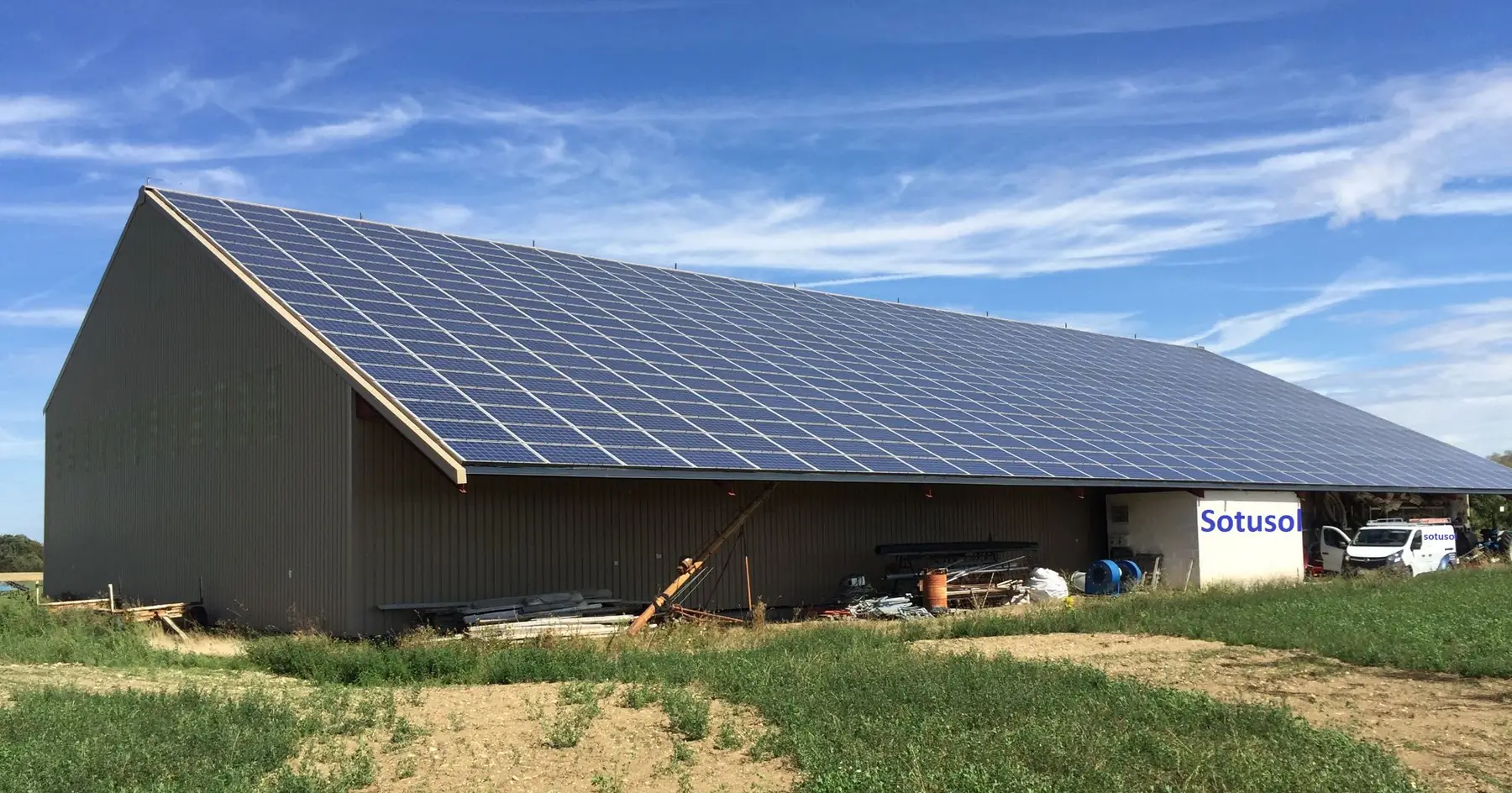 Bâtiment agricole couvert de panneaux solaires, la camionnette Sotusol devant